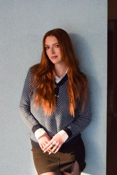 Portrait of a fashionable woman with auburn hair, showcasing modern style in a sweater and skirt.