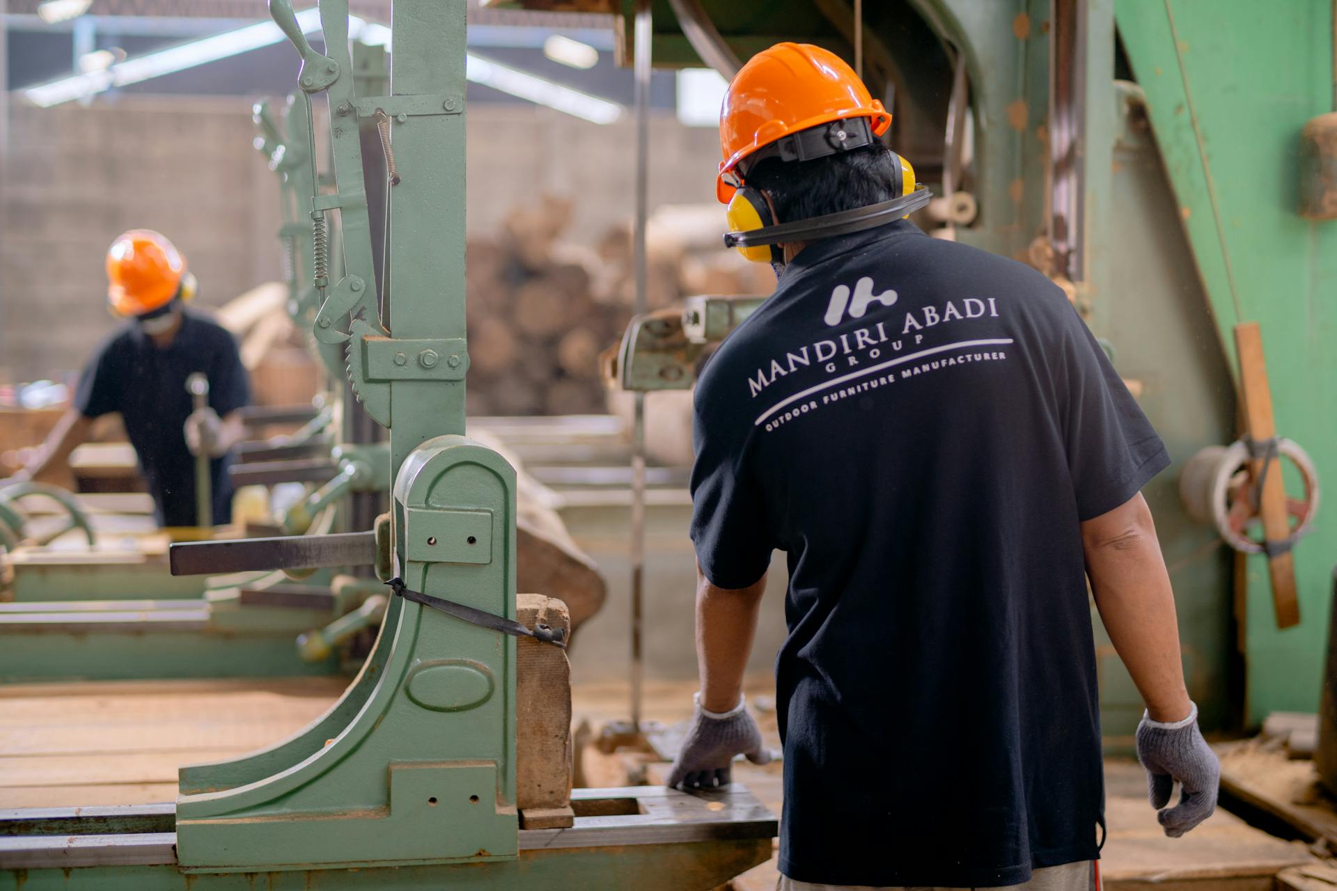 Workers wearing protective gear operating machinery in a factory environment, focusing on safety and production.