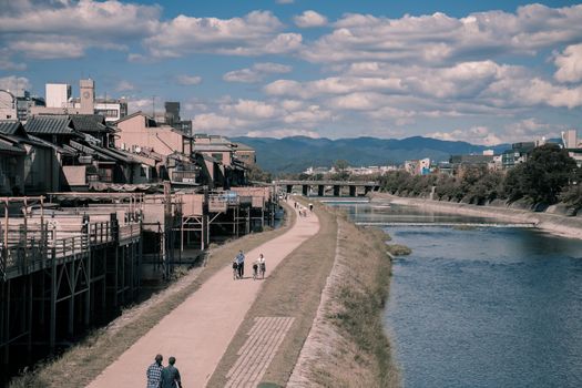 在日本京都一条风景优美的河畔小路上，人们悠闲地散步