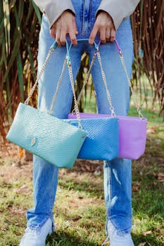 Person holding vibrant sling bags against a natural backdrop.