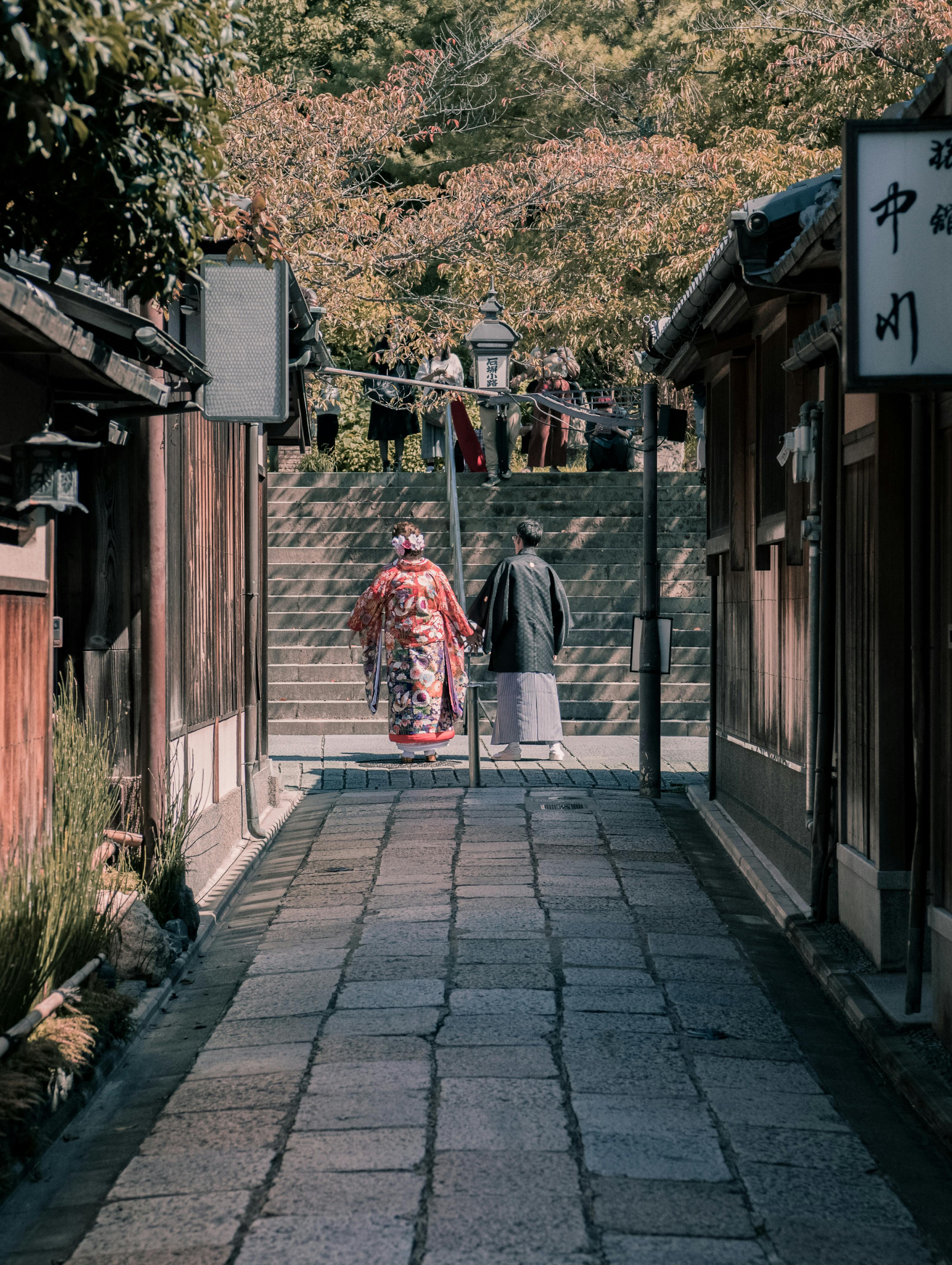 在日本京都的一条历史悠久的街道上，一对穿着和服的传统夫妇走过