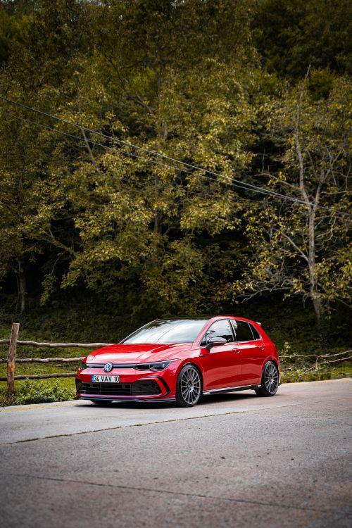 Free Red Volkswagen parked on a forest road surrounded by trees and wooden fence. Stock Photo