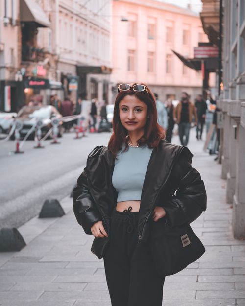 Free Elegant young woman in a black jacket posing confidently on a bustling urban street. Stock Photo