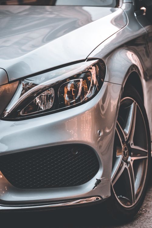 Free Detailed view of a sleek silver car's headlight and wheel, emphasizing modern automotive design. Stock Photo