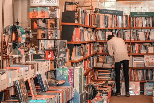 Free A person browses a vibrant selection of books in a cozy Brașov bookstore. Stock Photo