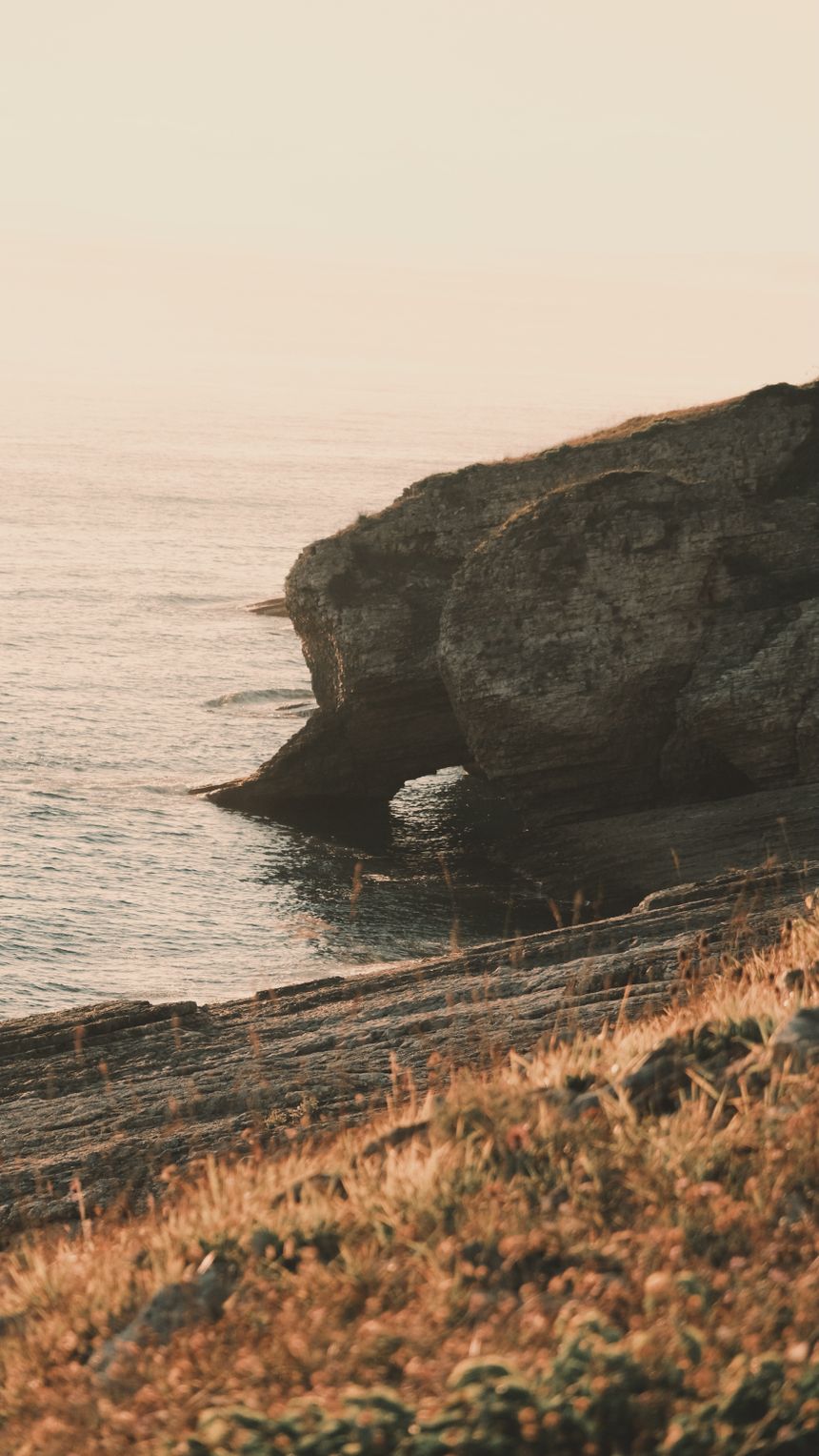 Rugged coastal cliffs above a shimmering sea — photo by Mustafa Çimen on Pexels