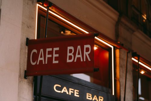 Free Stylish cafe bar sign illuminated with neon lights in urban setting. Perfect for restaurant and nightlife themes. Stock Photo