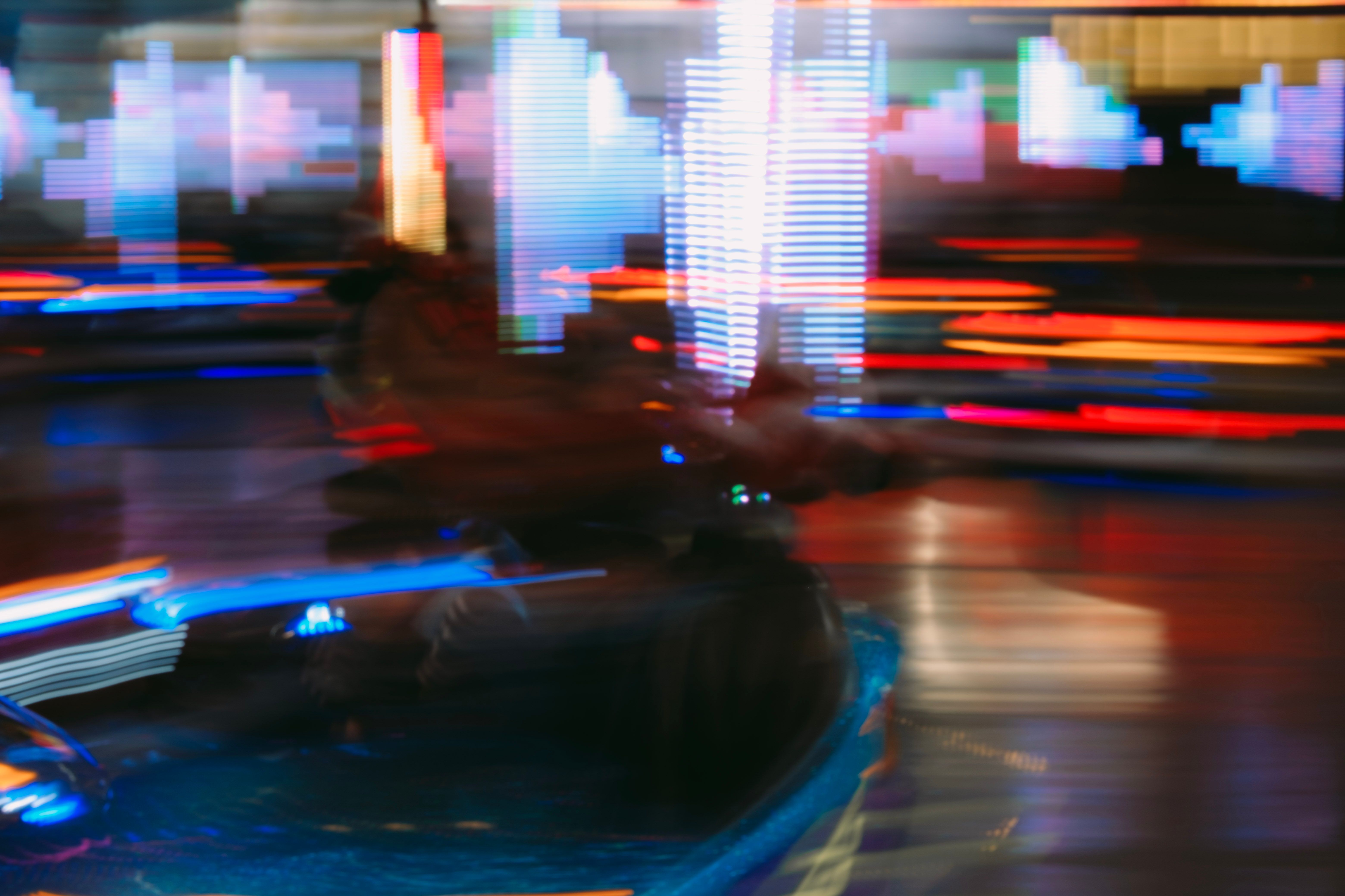Blurred motion capture of a neon-lit amusement park scene, full of vibrant colors and lights.