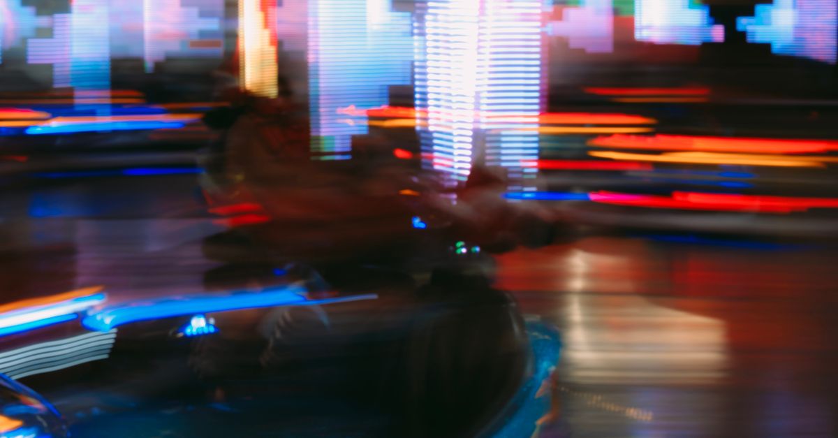 Blurred motion capture of a neon-lit amusement park scene, full of vibrant colors and lights.