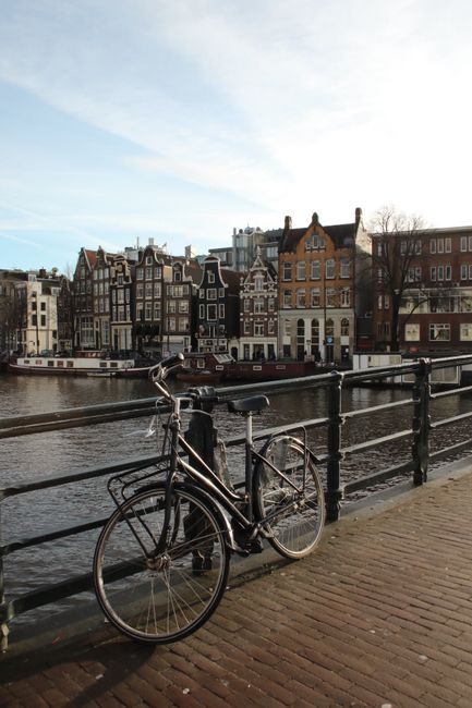 A classic Amsterdam bicycle on a bridge overlooking the iconic canal and traditional buildings.