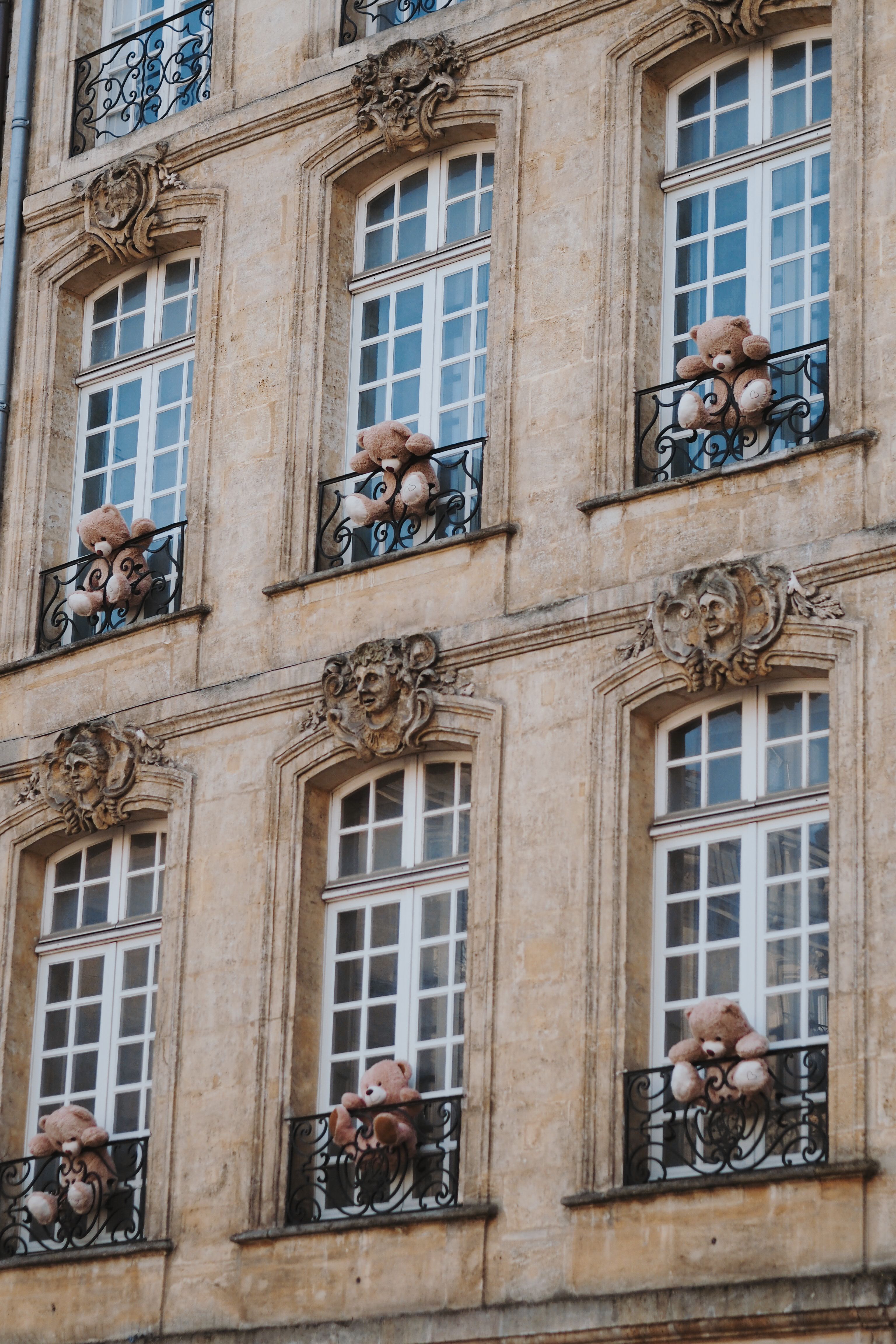 Historical building facade with teddy bears on balconies, creating a whimsical atmosphere.