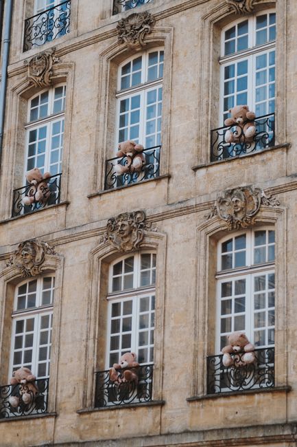 Historical building facade with teddy bears on balconies, creating a whimsical atmosphere.