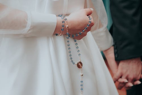 A Person Holding a Blue Rosary During a Ceremony