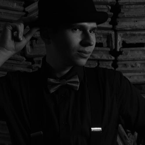 Grayscale Portrait of a Young Man in a Hat and Bowtie