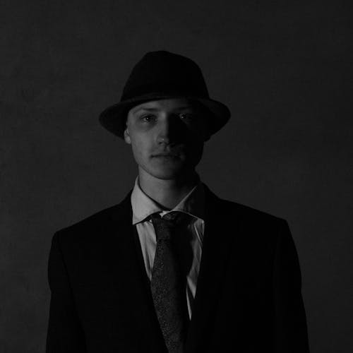 Grayscale Photo of a Man in a Suit Wearing a Hat