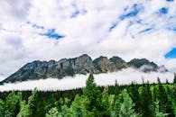 雄伟的山脉、茂密的森林与天空中的云彩，共同展现了大自然的美丽