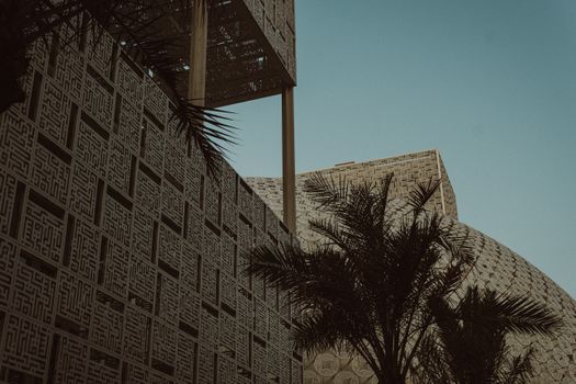 Stunning view of modern Islamic architecture with palm trees under a clear blue sky in Kuwait City.