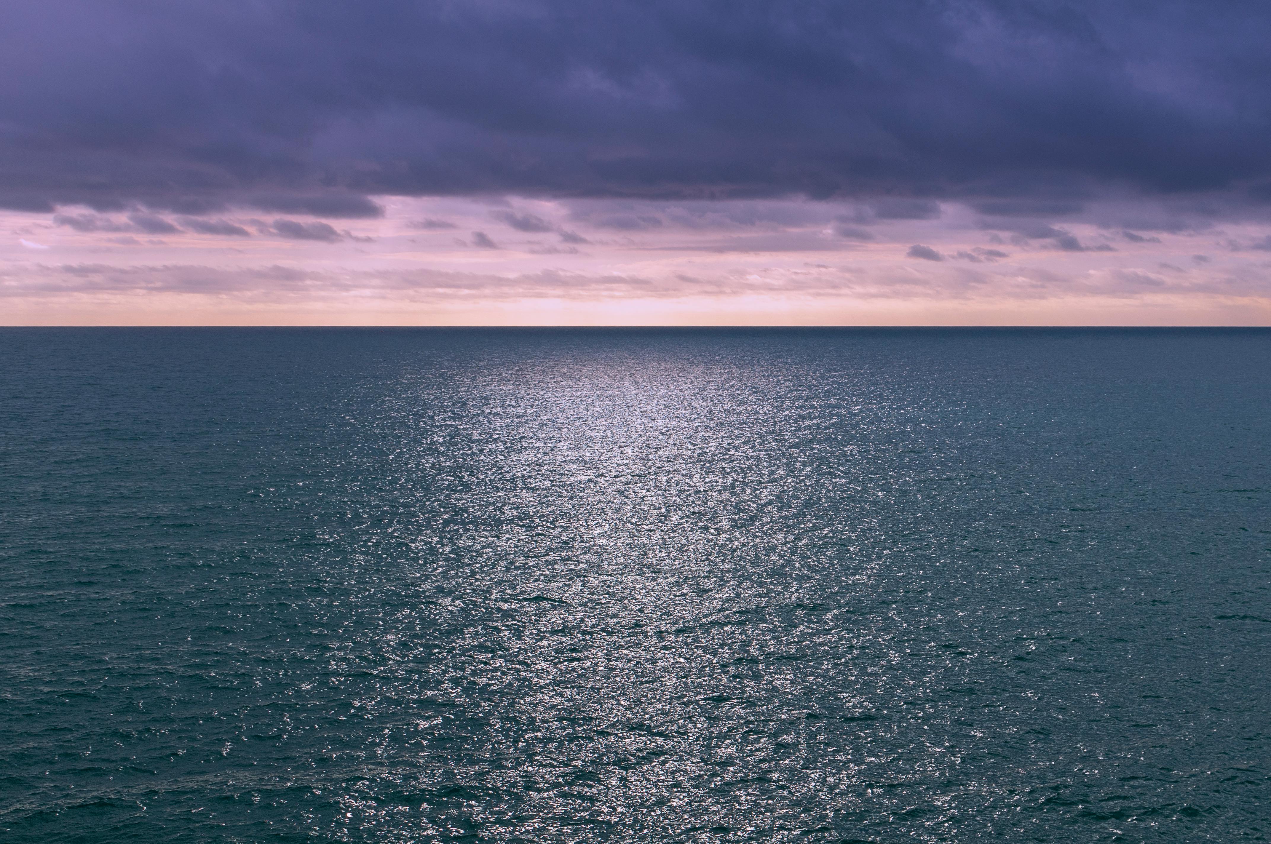 Costa mediterránea al anochecer con nubes serenas en horizonte.