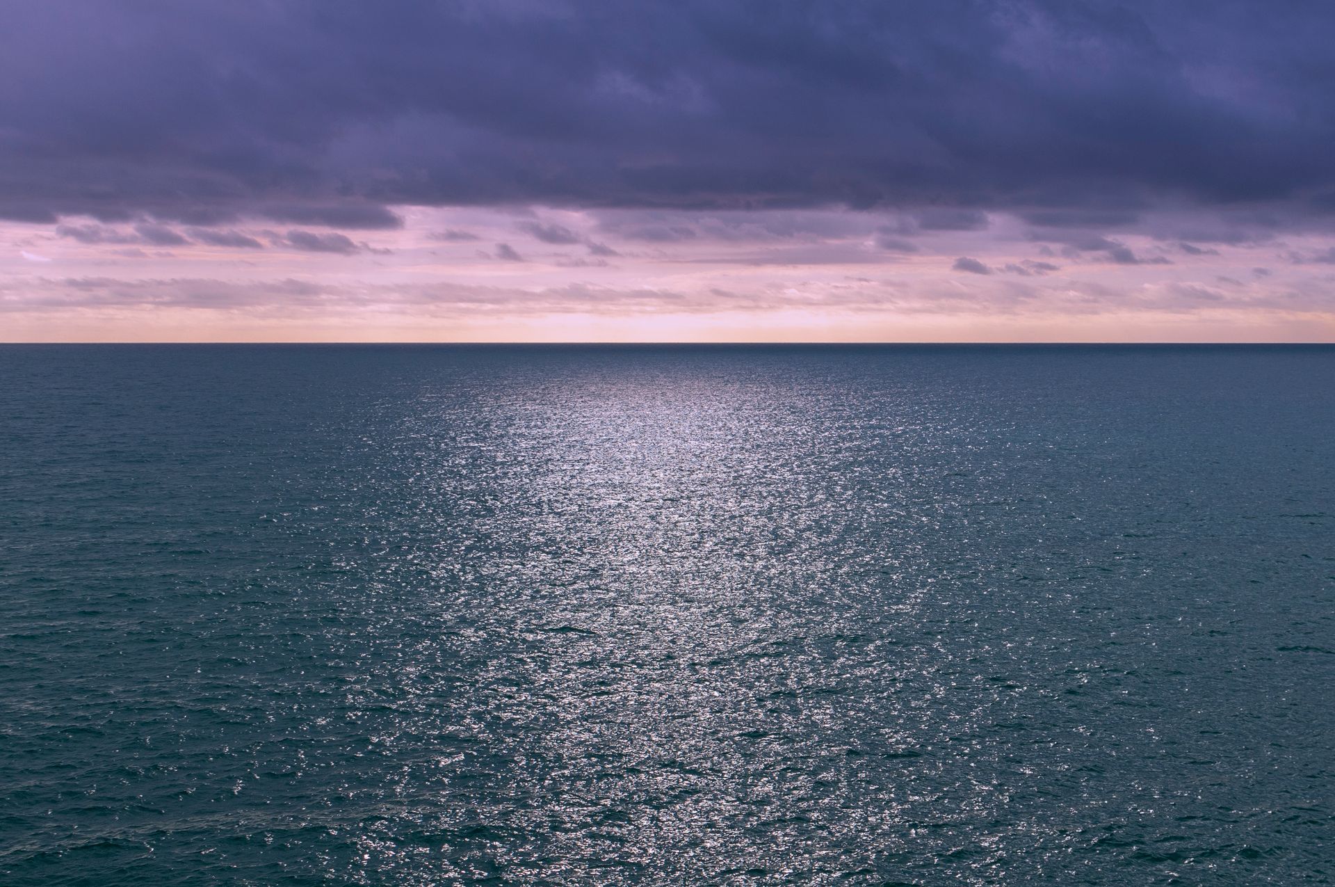 Costa mediterránea al anochecer con nubes serenas en horizonte.