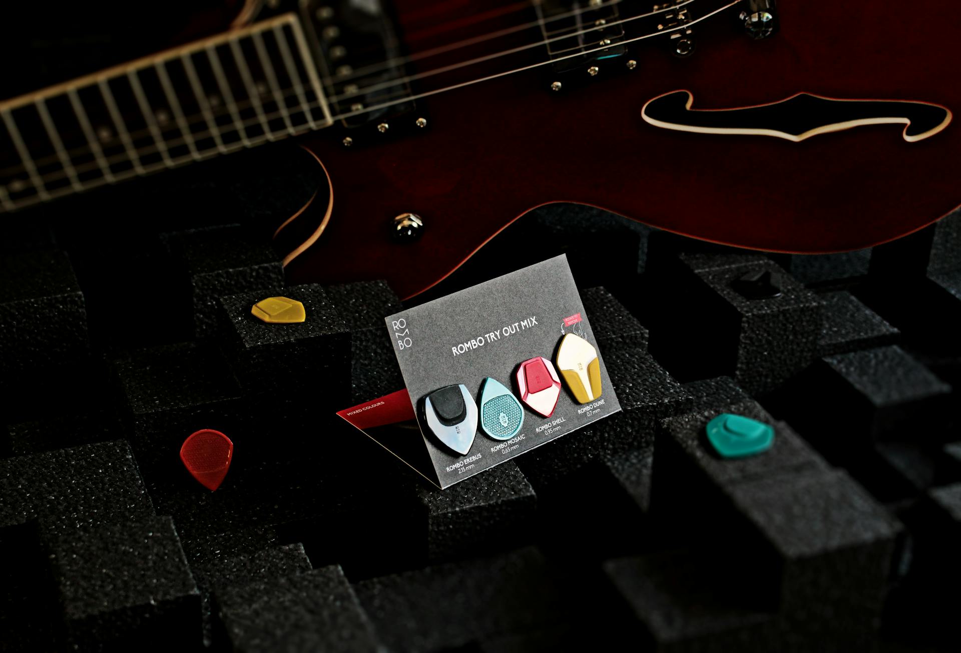 Detail shot of an electric guitar with assorted guitar picks on black foam background.