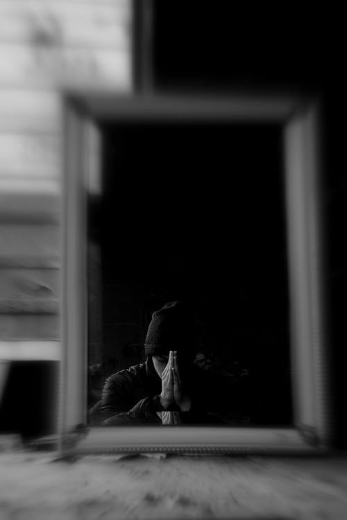 Free A Grayscale of a Reflection of a Man Praying Stock Photo