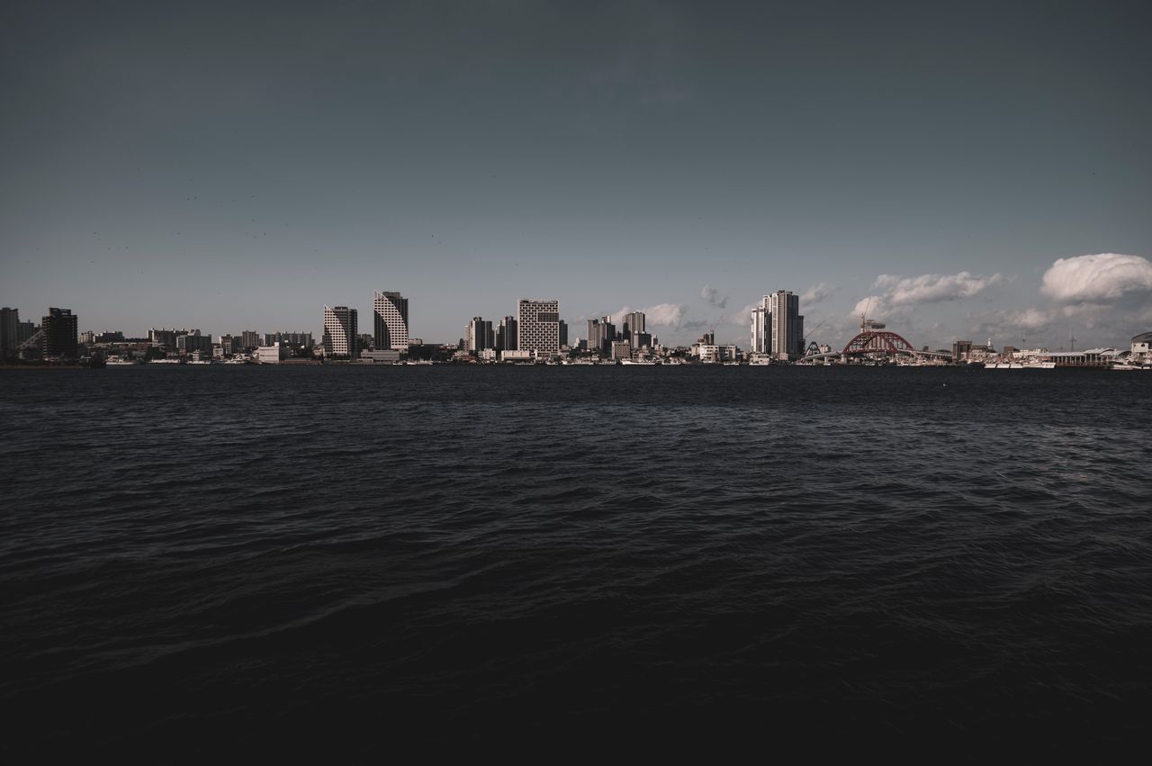 dramatic city skyline viewed across a vast body of water under a moody