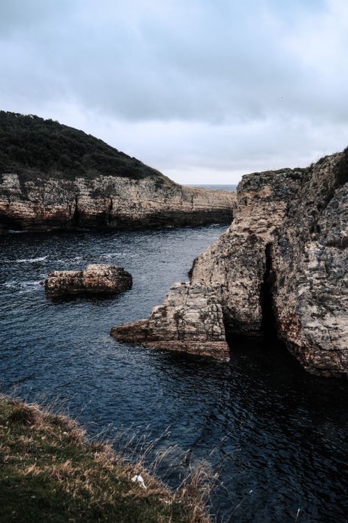 Free Scenic cliffside overlooking a tranquil lake under a cloudy sky, perfect for nature lovers. Stock Photo