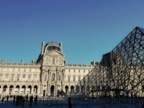 Free The Louvre Museum and Pyramid under a blue sky in Paris, a must-see landmark. Stock Photo