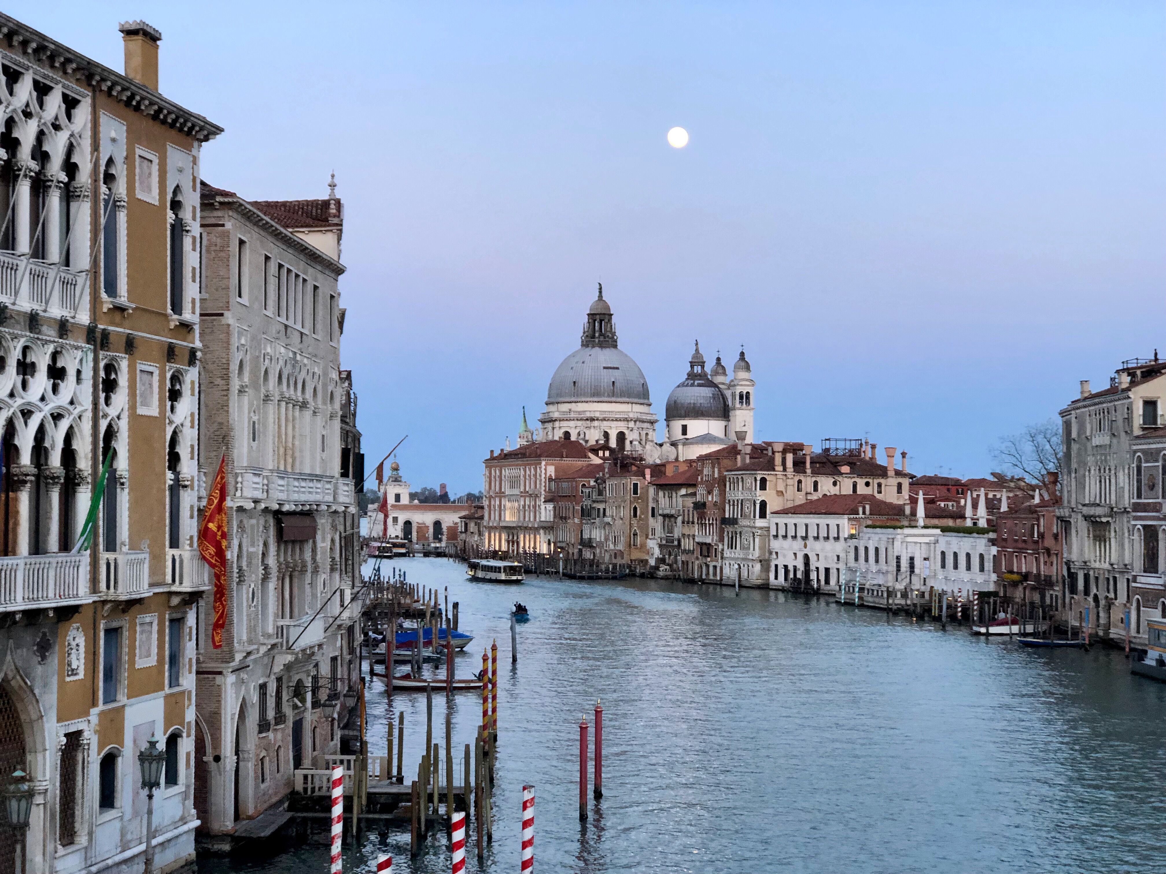 Linda vista do Grande Canal em Veneza à noite sob a lua cheia, mostrando uma arquitetura pitoresca.