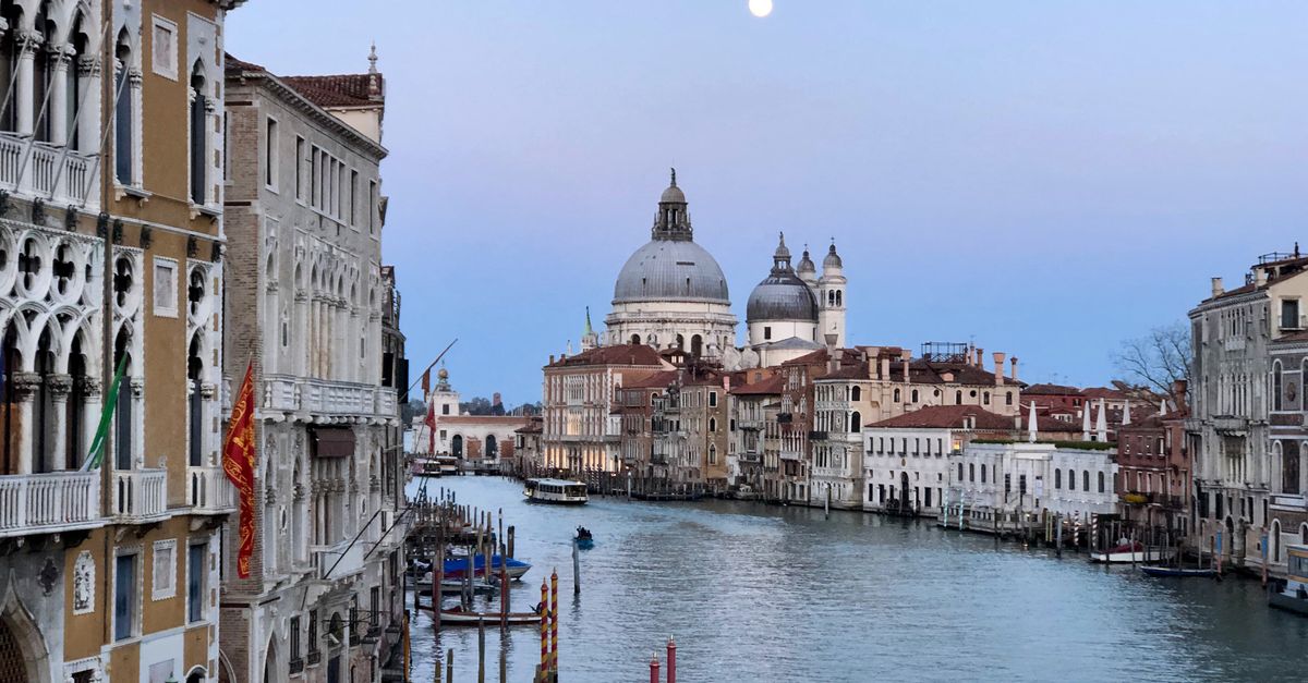 Linda vista do Grande Canal em Veneza à noite sob a lua cheia, mostrando uma arquitetura pitoresca.