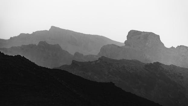 A stunning black and white image showcasing the layered mountains under soft light.