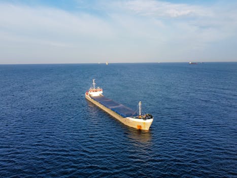 A cargo ship moves through the ocean, captured from above in a seascape scene.