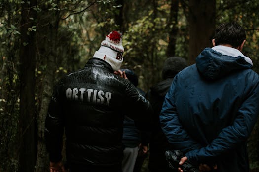 A group of adults hiking through a lush, rainy forest, wearing winter clothes.