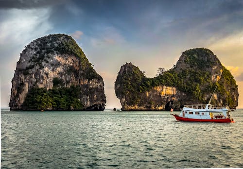 White Boat Sailing Near Islands during Golden Hour