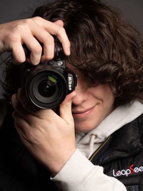 Free A young photographer capturing a shot with a Nikon camera, focusing on creativity and passion. Stock Photo