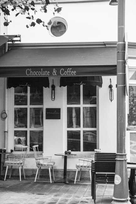 Charming black and white façade of a café with outdoor seating arrangement.