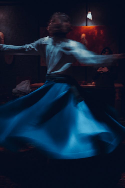 Blurry Photo of Woman in Long Blue Skirt Dancing