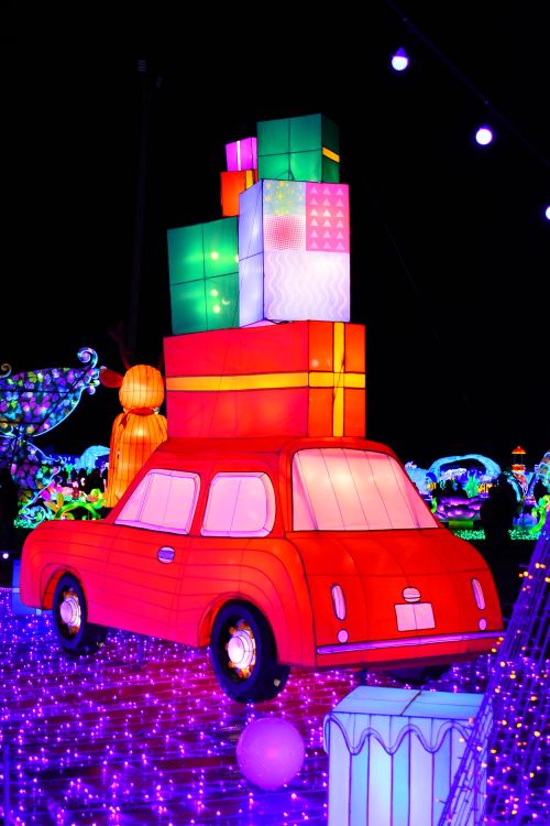 Free A colorful illuminated car with gift boxes, perfect for festive holiday celebrations. Stock Photo