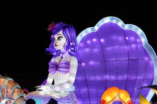 Colorful illuminated mermaid decoration at a night carnival, showcasing vibrant fantasy art.