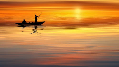 Free Silhouette Boat and Man Sailing on Ocean Stock Photo