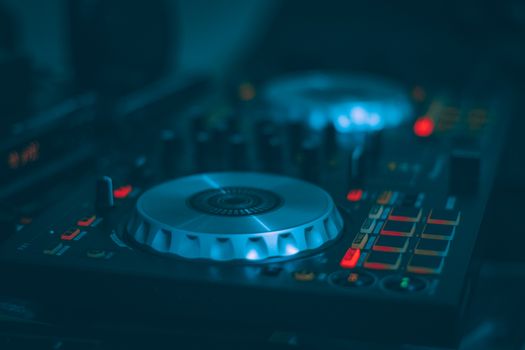 A detailed shot of a DJ mixer with illuminated buttons and controls, ideal for music and technology themes.