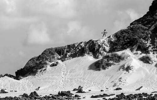 Person Holding Surfboard on Cliff