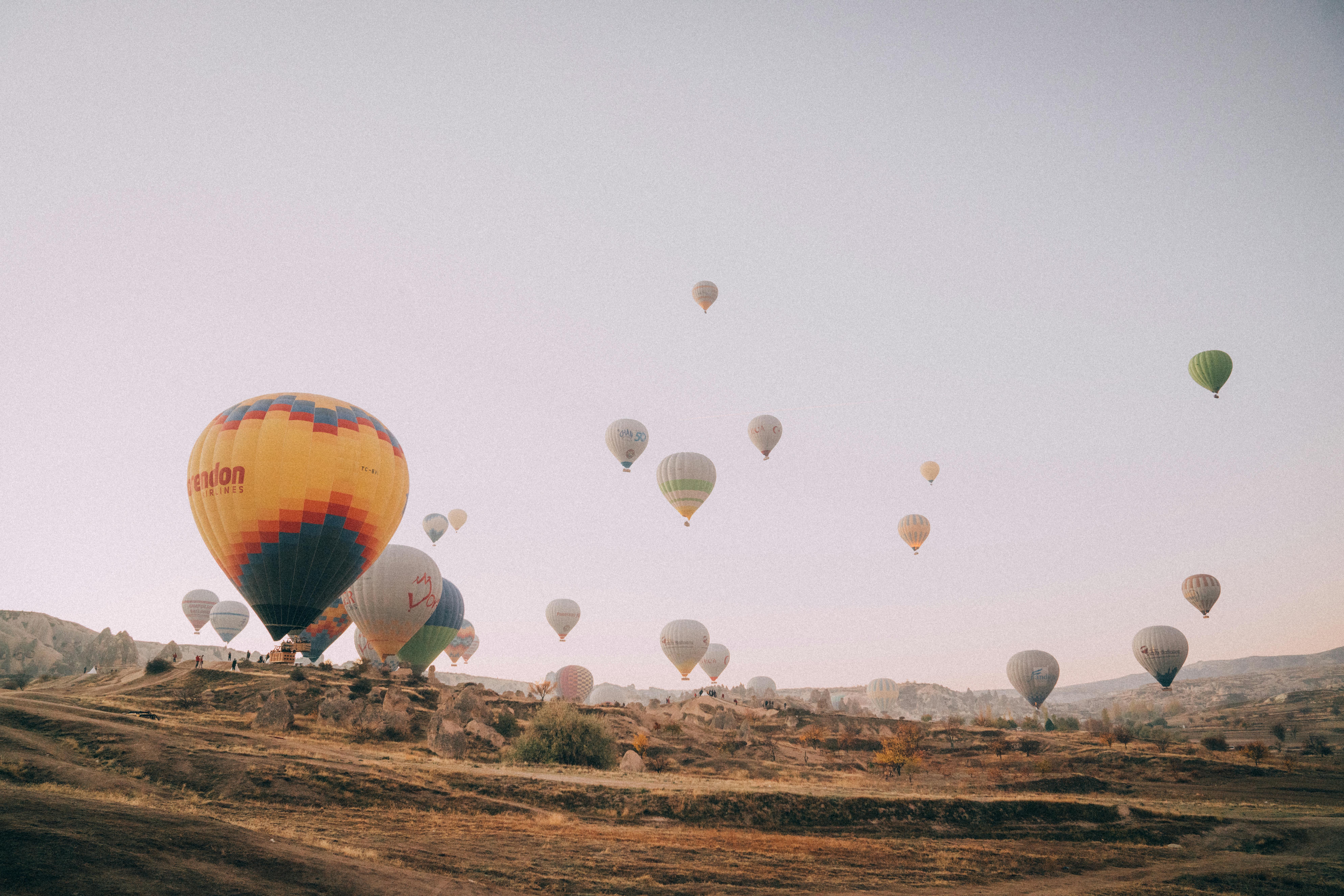 Vibrant hot air balloons floating above the unique rock formations of Cappadocia during sunrise.
