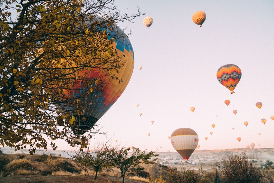 Stunning view of colorful hot air balloons soaring over Cappadocia at sunrise.