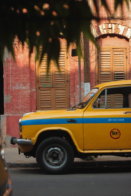 Classic yellow taxi parked on an urban street with a rustic backdrop, embodying a nostalgic city vibe.