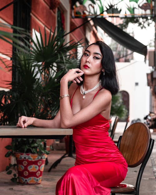 Beautiful Woman in a Red Dress Sitting at a Table 