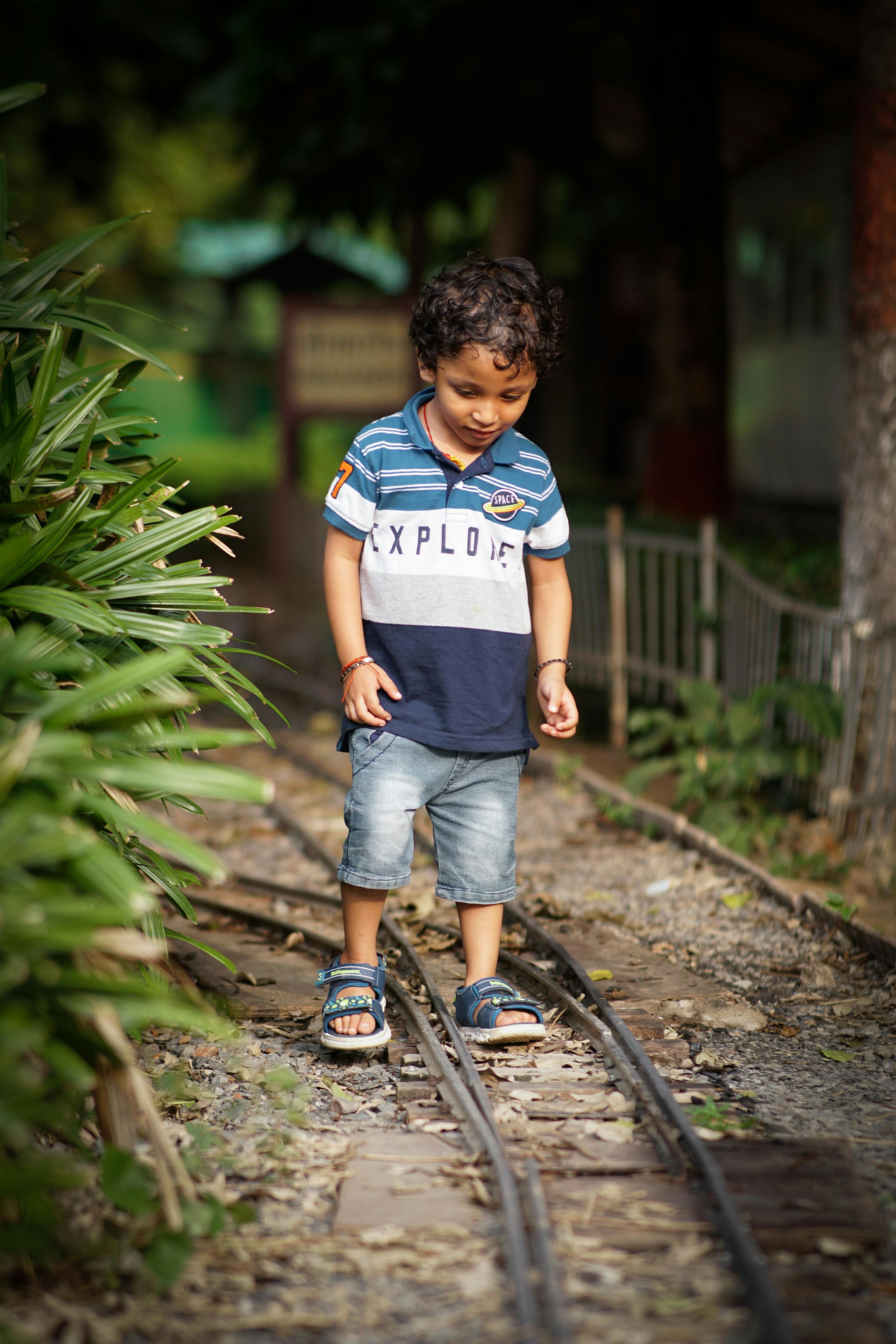 a young boy in denim shorts standing on railway