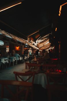 Atmospheric nighttime view of a cozy rustic restaurant with warm lighting and people dining inside.