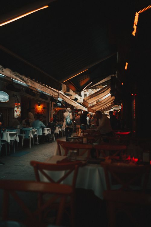 Free Atmospheric nighttime view of a cozy rustic restaurant with warm lighting and people dining inside. Stock Photo