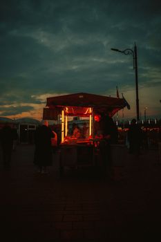 Captivating street scene with a lit food stall under a dramatic evening sky.